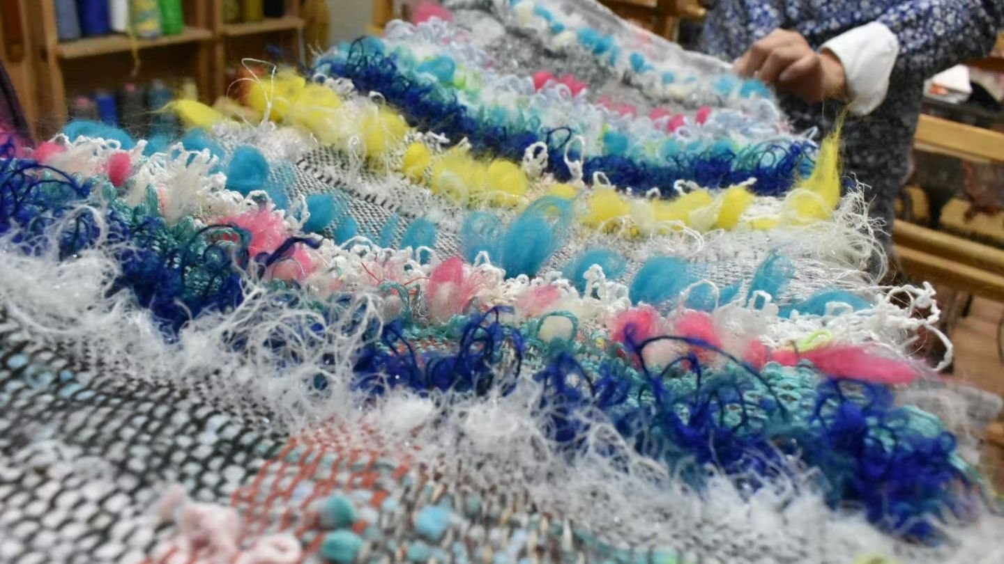 Workshop staff assisting a participant at the loom