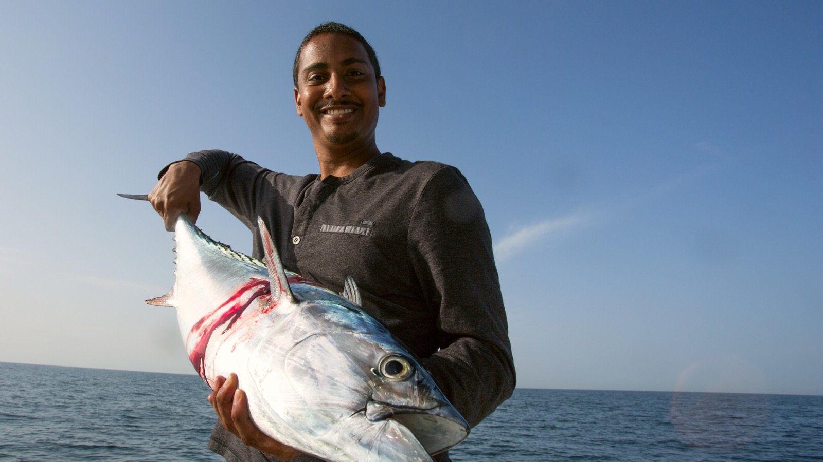Group holding a barracuda catch on a sunny day