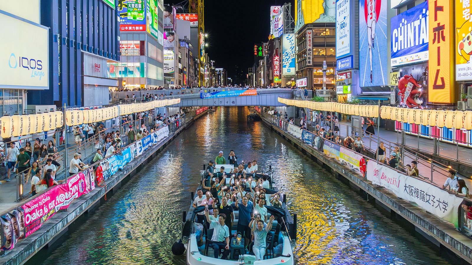 Passengers viewing iconic riverside landmarks from the sightseeing boat in Osaka