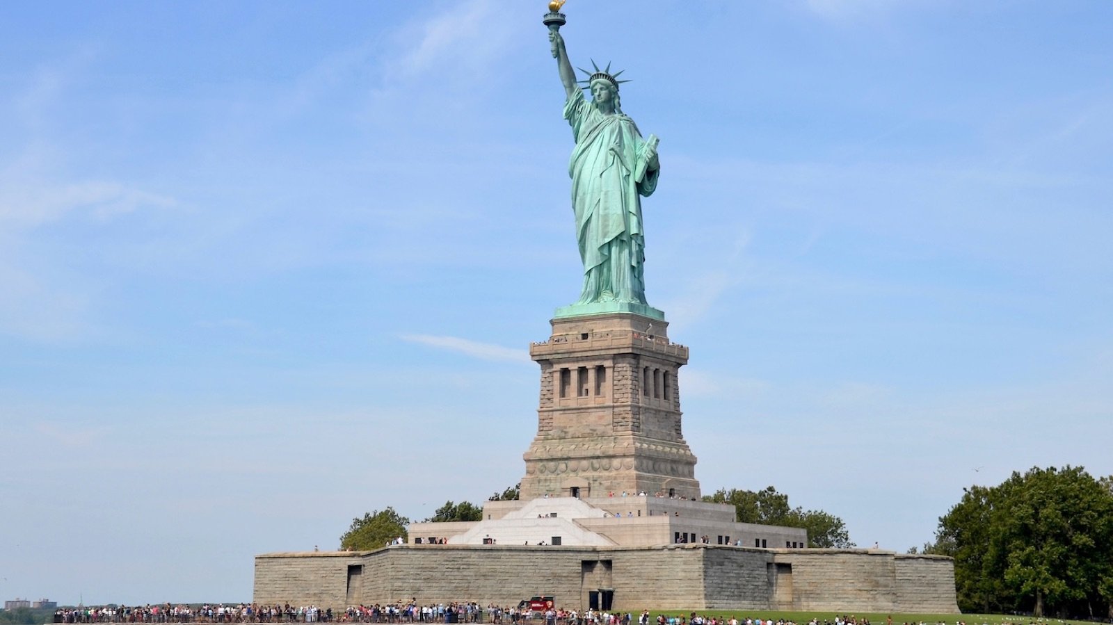 Visitors walking the grounds of Liberty Island with audio guides